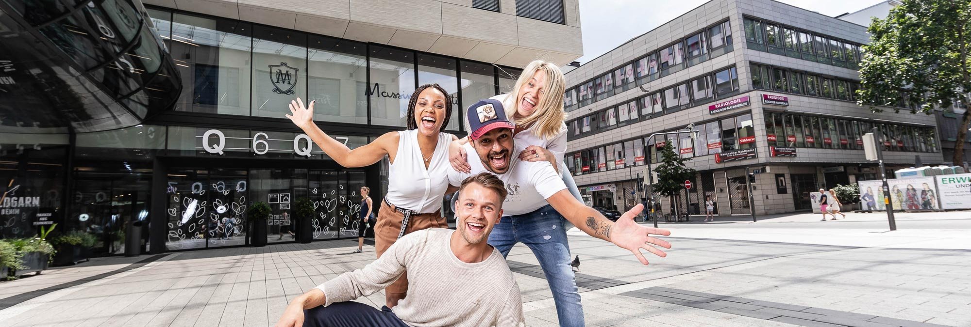 Dieses Bild zeigt vier Personen, die fröhlich auf dem Münzplatz zusammen lächeln. 